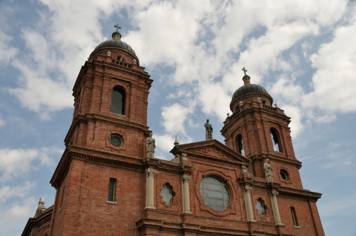 The Saint Lawrence Basilica in Asheville, North Carolina against a vivid blue sky with fluffy clouds. Nikon D300 (RAW).