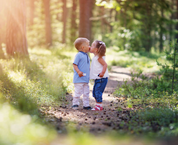 Boy and boy kissing in the forest in summer