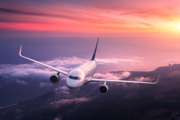 istock Big airplane is flying in red sky over the clouds 935091324