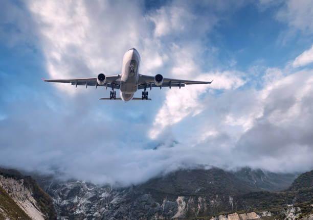 istock Big white airplane is flying in cloudy sky at sunset 935091344