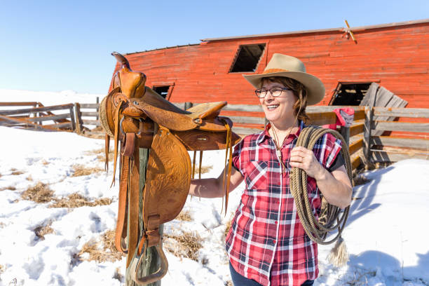 istock happy cowgirl standing next to her saddle holding a rope. 935091350