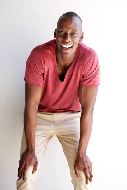 young african american man laughing with hands on knees Portrait of young african american man laughing with hands on knees hand on knee stock pictures, royalty-free photos & images