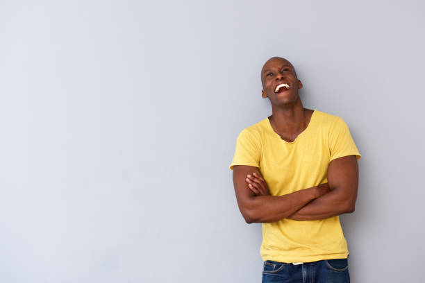 istock happy black guy leaning against gray wall and looking up 935110456
