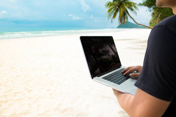 istock Casual man using laptop computer working and traveling in summer beach 935110602