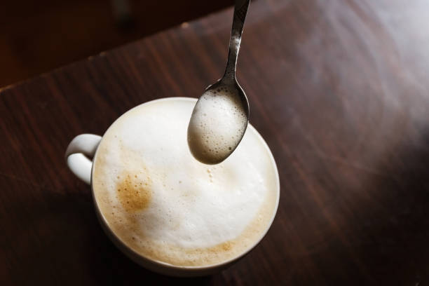 istock Cup of coffee with foam being stirred by a human hand 935125184