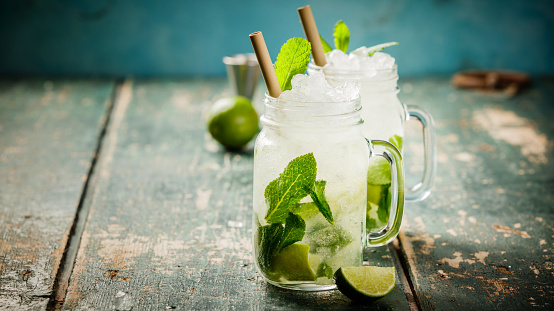 Mojito cocktail with lime and mint in glass jars on the table. Copy space