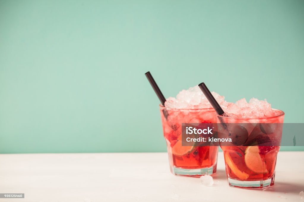 Red drink with ice Red drink with ice. Cocktail making bar tools, raspberry, lime, oranges and mint leaves. Raspberry mojito on blue background Cocktail Stock Photo