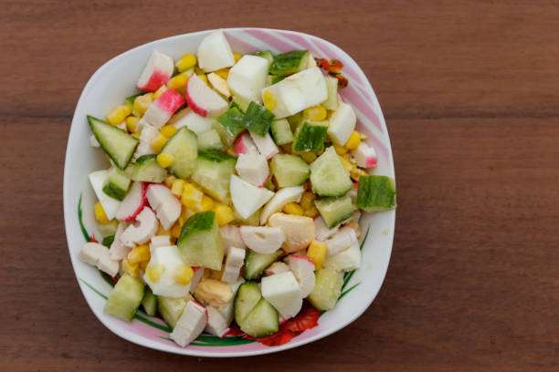 istock Salad with crab sticks, sweet corn, cucumber and eggs on wooden table 935125510