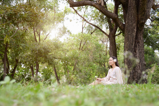 istock Beautiful woman sitting against tree in summer park. 935139218