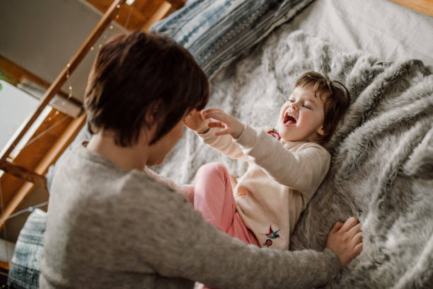 istock Mother and daughter playing in bed 935145032