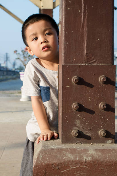 The child hides behind a pole.Expressions of concern.