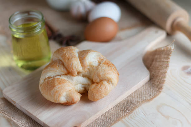 istock Croissant on wooden cut board on table wood and fabric select focus shallow depth of field 935217536