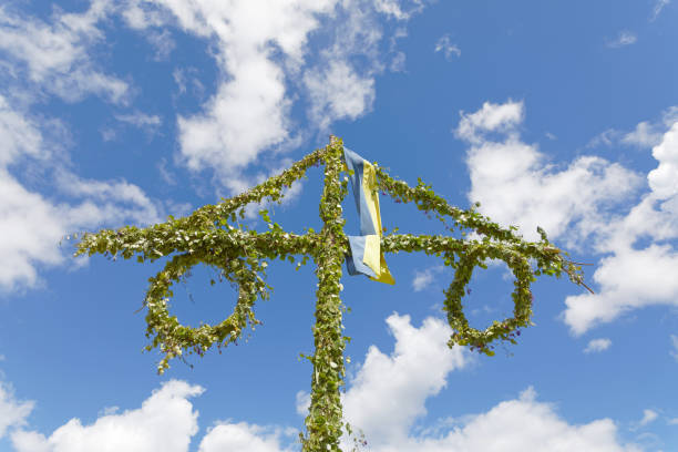 istock Maypole made of green leaf and the blue sky and some white clouds behind 935226242