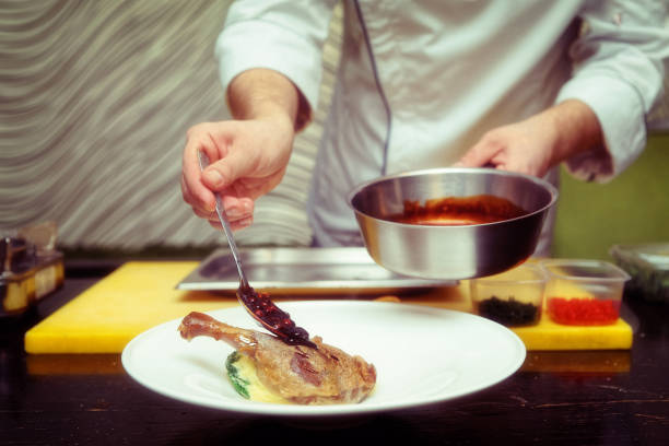 istock Chef is adding berry sauce to poultry dish, toned 935226402