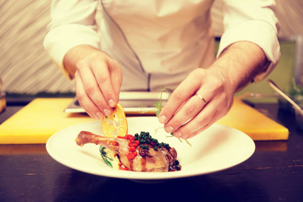 istock Chef is decorating a dish with dried orange and pea sprout, toned 935226792