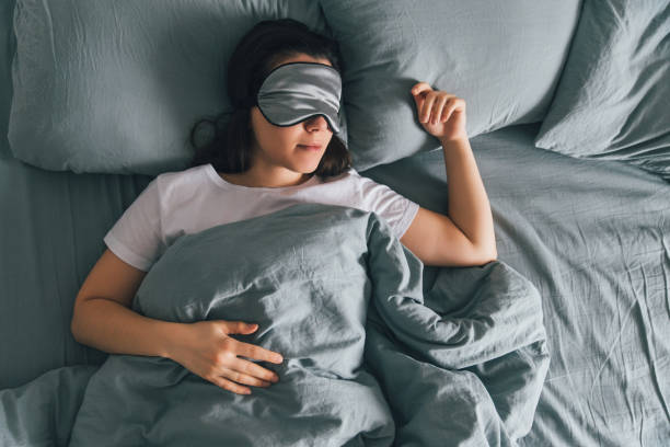 woman sleep in eye patch in grey bed. copy space - sheet sleeping women bed imagens e fotografias de stock