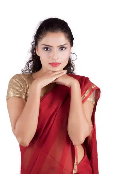 Portrait of pretty girl looks pensive while wearing red saree, isolated on white background