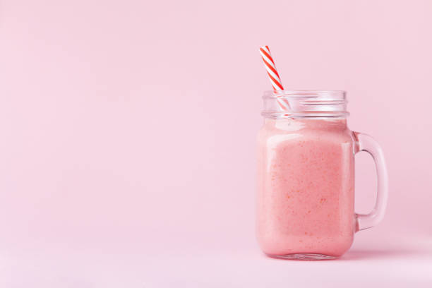 erdbeer smoothie oder milchshake im einmachglas auf pastell rosa hintergrund. gesunde lebensmittel für frühstück und snacks. - mason stock-fotos und bilder