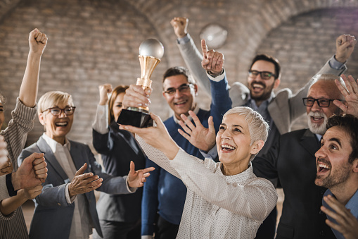 Large group of cheerful business people with a trophy in the office.