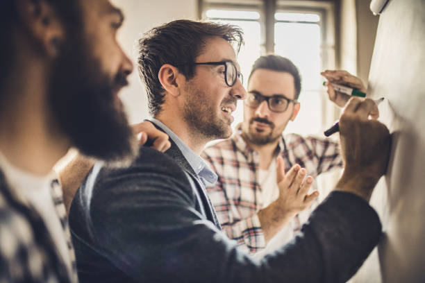 istock Male team of entrepreneurs cooperating while writing a business plan on whiteboard. 935254392