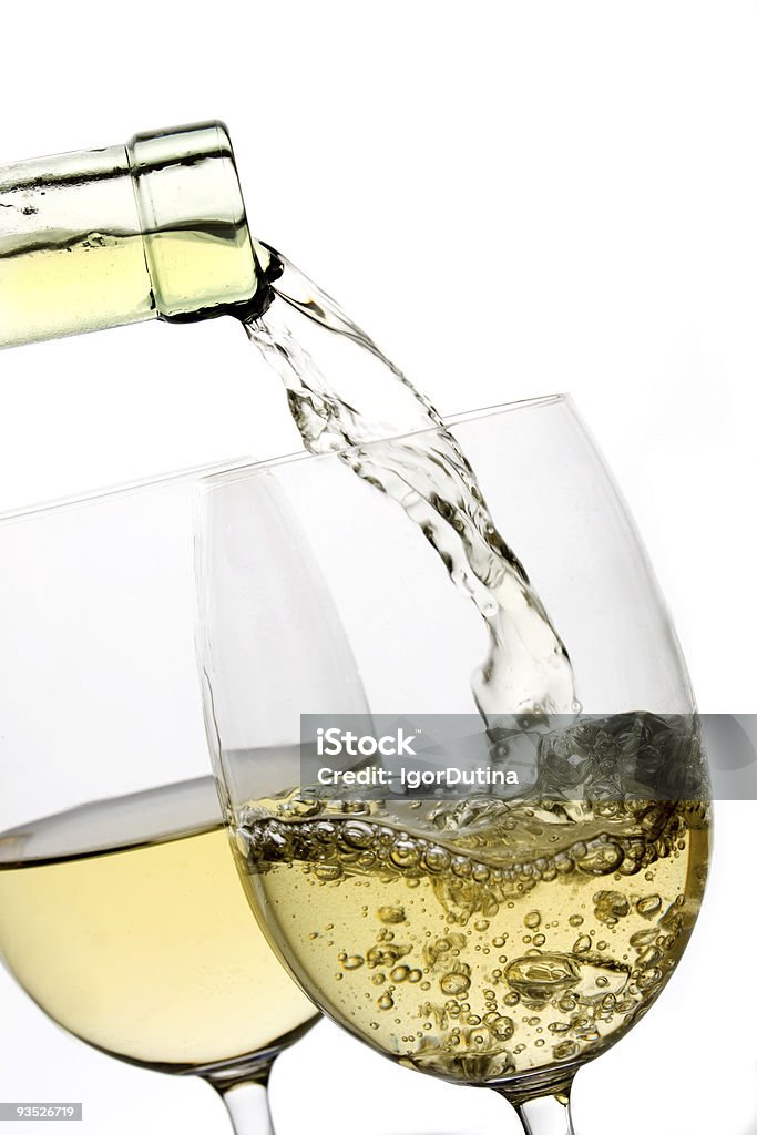 White wine being poured into a glass on a white backdrop White wine poured in a glass over white background White Wine Stock Photo