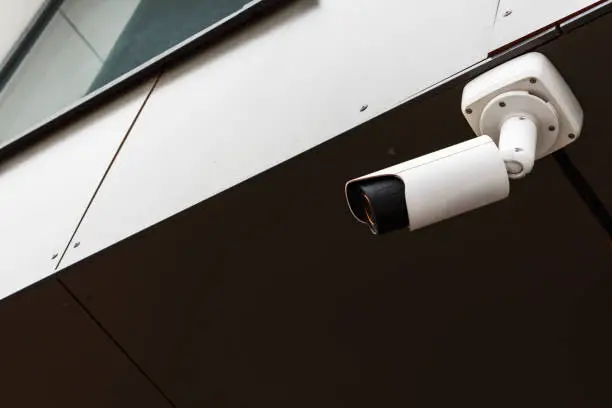 Modern white CCTV security camera on the building observes