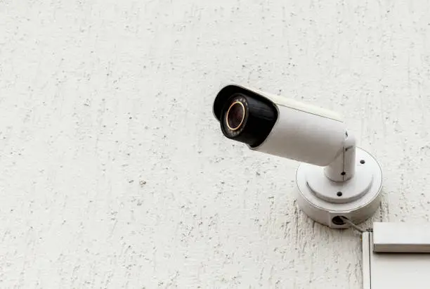 Modern white CCTV security camera on the building observes. Copy space