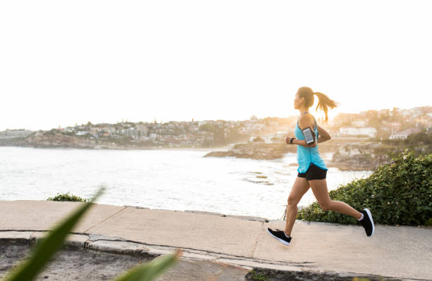 Woman Running Young asian woman running near the seaside sports training australia stock pictures, royalty-free photos & images