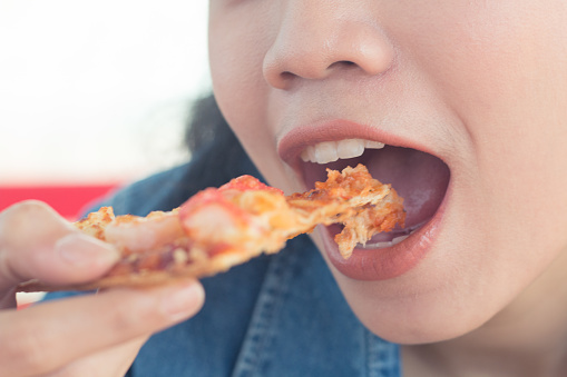 close up asian woman  hand holding pizza and eating vinatge tone