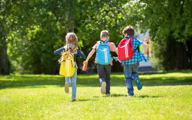 istock Children with rucksacks standing in the park near school 935290854