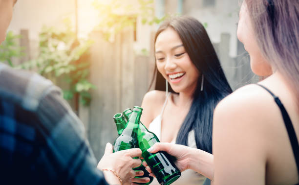 istock Young asian people holding beer bottles and clink with drinking together. 935298040