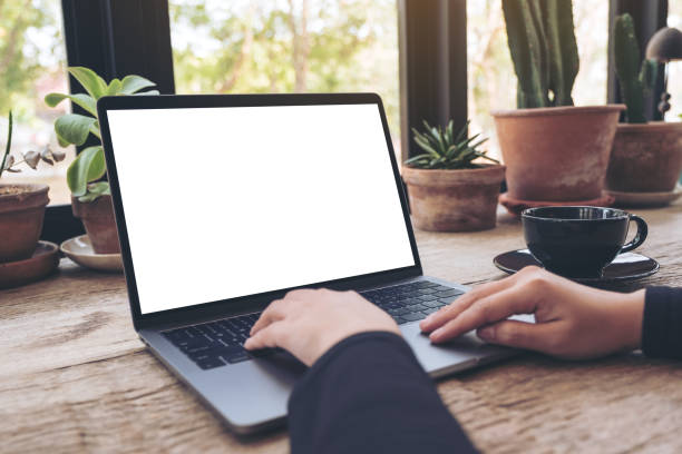 istock Mockup image of hands using and typing on laptop with blank white desktop screen on vintage wooden table in cafe 935301618