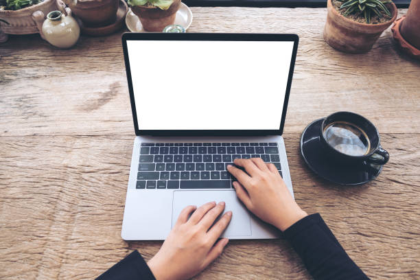 istock Top view mockup image of hands using and typing on laptop with blank white desktop screen on vintage wooden table in cafe 935302010