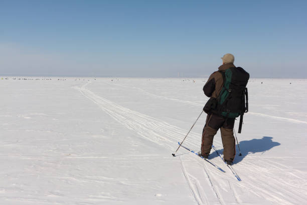 istock Man with a backpack is skiing on a snowy river,Ob Reservoir, Russia 935304722