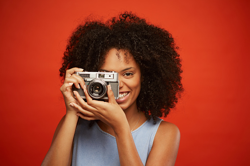 Person holding an old analog camera on a black isolated background.