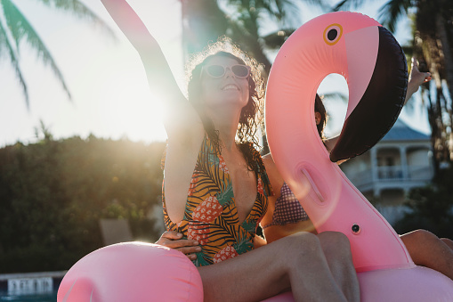 Amigas con inflable flamingo durante fiesta de piscina photo