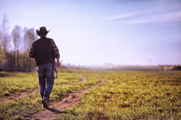 istock Cowboy standing in a field at sunset 935305480
