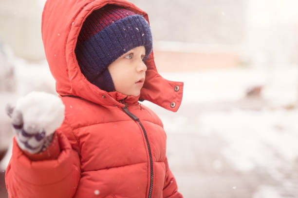 istock Baby boy with snowball while snowing 935305498