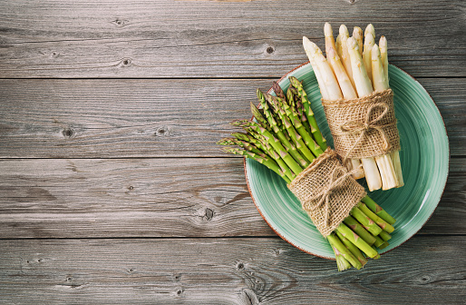 Bunches of fresh green and white asparagus on wooden background