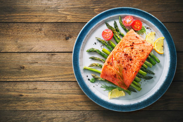 grilled salmon garnished with green asparagus and tomatoes - prepared fish seafood barbecue grilled imagens e fotografias de stock