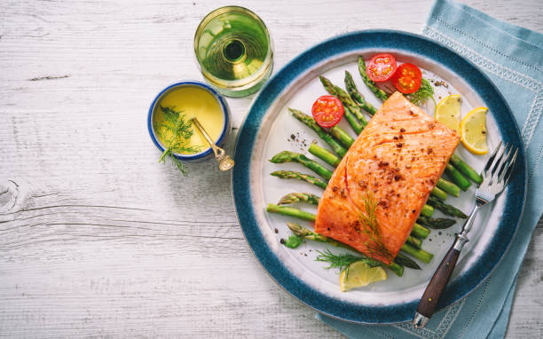 Grilled salmon garnished with green asparagus and tomatoes Grilled salmon garnished with green asparagus and tomatoes.Top view hollandaise sauce stock pictures, royalty-free photos & images