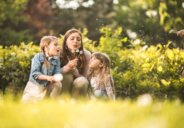istock Mother and daughters enjoying in nature blowing taraxacum 935324686