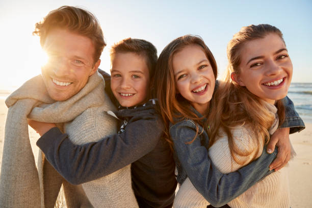 Parents Giving Children Piggyback Rides On Winter Beach