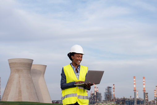 Woman engineer checking the data of the oil refinery, using a laptop computer.