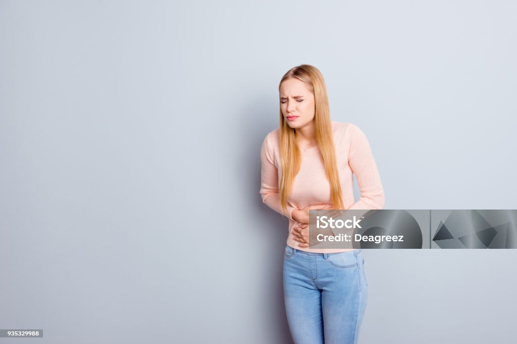 Portrait of sad unhappy upset stressed frustrated depressed crying troubled nervous bad negative feeling woman touching holding tummy with hands isolated on gray background copy-space One Woman Only Stock Photo