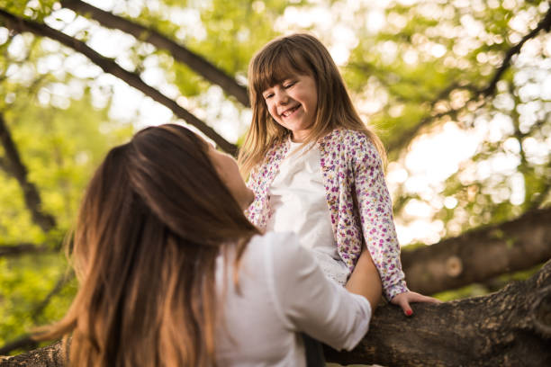 istock Back view mother helping a small daughter to get down from tree 935330046