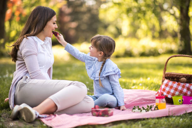 istock Mother and daughter eating strawberries in park 935334896