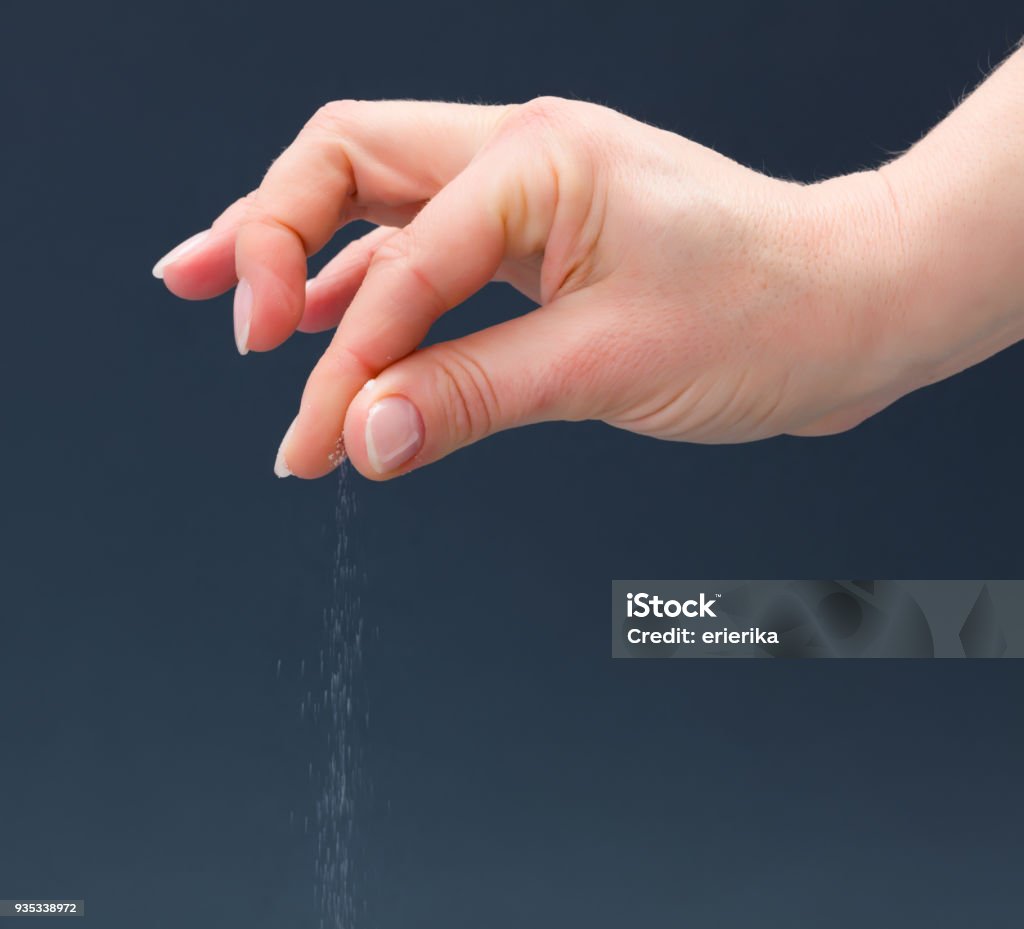 Hand sprinkling salt Hand sprinkling salt on gray background Salt - Seasoning Stock Photo