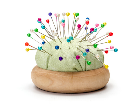Wooden pincushion full with with colorful pins