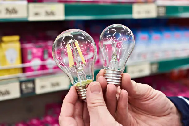 LED and incandescent lamp in the hands of the buyer in the store